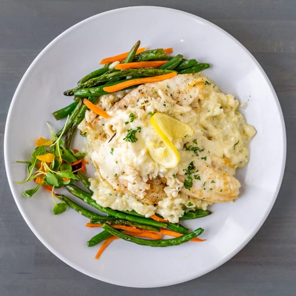 Hutchinson Island Bar and Grille's fish with creamy sauce, green beans, carrots, and a lemon wedge.