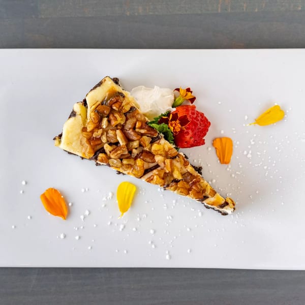Hutchinson Island Bar and Grille's pecan cheesecake slice with whipped cream, strawberry, and flower petals.